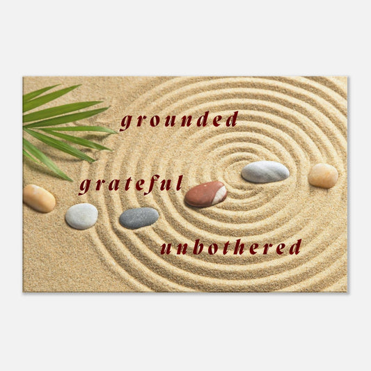 Spiritual canvas art with quote "Grounded, Grateful, Unbothered" and meditation stones on sand

