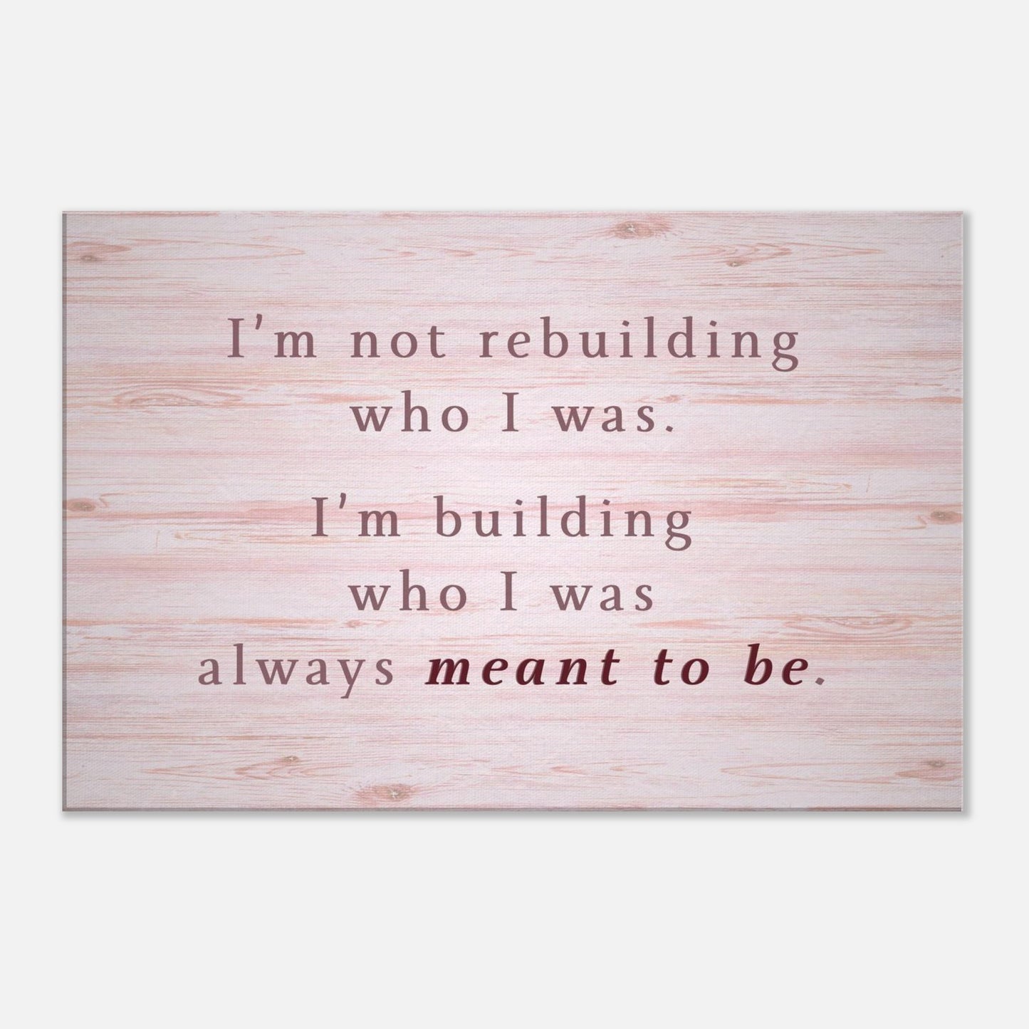 Inspirational canvas wall art with quote “I’m building who I was meant to be” on pink wood background

